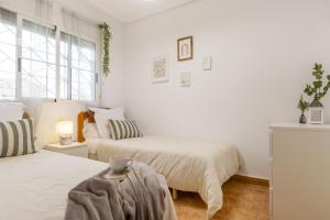 a white bedroom with two beds and a table at Bungalow Pink Lagoon in Torrevieja +29 photos