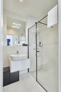 a white bathroom with a sink and a shower at Wave - Aurum II Apartment - Front Sea View in Międzyzdroje