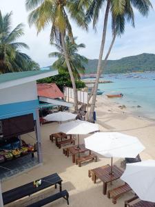 a beach with tables and chairs and palm trees at Perhentian Bay Chalet in Perhentian Islands