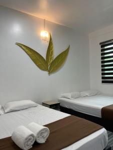 a bedroom with two beds and a large leaf on the wall at Perhentian Bay Chalet in Perhentian Islands