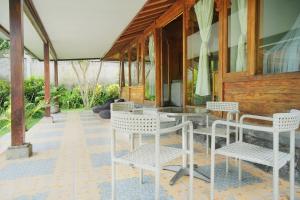 a patio with white chairs and a glass table at Javanese Joglo House by Malathi Ubud in Ubud