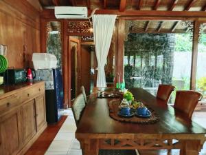 a kitchen with a wooden table with chairs and a tableasteryasteryasteryasteryastery at Javanese Joglo House by Malathi Ubud in Ubud
