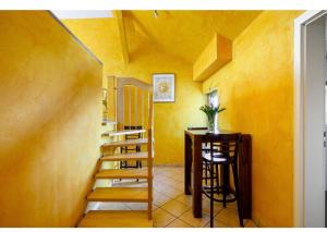 um quarto amarelo com uma escada e uma mesa em Hirschen Apartments em Reute