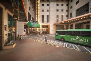a green bus parked in the middle of a building at Al Kiswah Towers Hotel in Makkah