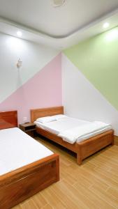 two beds in a room with pink walls and wooden floors at Nhà Nghỉ Thảo Tiên in Xóm Tràm Cửa