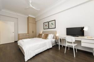um quarto branco com uma cama, uma secretária e uma televisão em VSummer CozyHaven 4br nr CIQ R&F by Our Stay em Johor Bahru