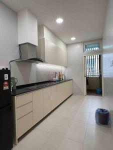 a kitchen with white cabinets and a black refrigerator at Romance's Getaways Riverine Homestay @ Kuching in Kuching