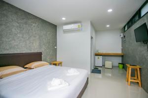 een slaapkamer met een groot wit bed en een keuken bij บ้านเราอุทัยธานี โฮมสเตย์ in Uthai Thani