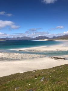 a beach with the ocean and mountains in the background at Urgha Bay in Tarbert