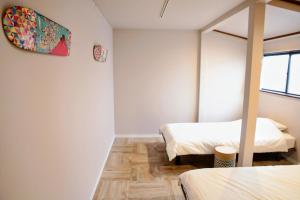 two beds in a room with white walls and wooden floors at Hokusai Stay in Osaka