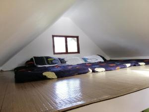 a large bed in a attic with a window at Uphill Cozy Cabins in an Island Lake for Family getaway in Cavinti