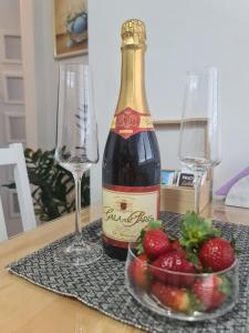 butelkę wina i miskę truskawek na stole w obiekcie Apartman Zlatovo Stan Na Dan w mieście Požarevac