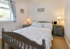 a bedroom with a bed and two night stands and a window at 243 Cae Du in Abersoch