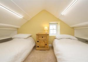 2 łóżka w pokoju na poddaszu z oknem w obiekcie Bryn Refail Bach w mieście Llanengan