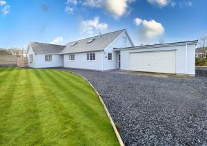 a white house with a garage and a yard at Llecyn in Pwllheli