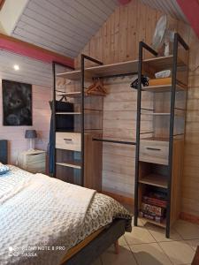 1 dormitorio con 1 cama y pared de madera en Les abris de la hulotte, en Anould