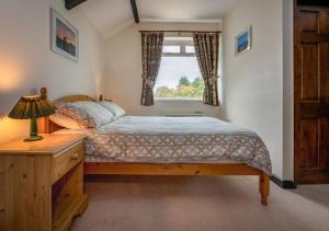 a bedroom with a bed and a window at Camellia Cottage in Llanbedrog