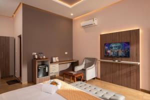 ein Schlafzimmer mit einem Bett, einem Stuhl und einem Fernseher in der Unterkunft Paradise Marari Boutique Resort and Ayurvedic Spa in Alappuzha