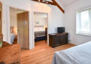 a room with a bedroom with a bed and a television at Y Stabl in Abersoch