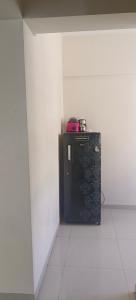 Akshra residency 1 bhk في هنجاودي: ثلاجة صغيرة سوداء في ركن من أركان الغرفة