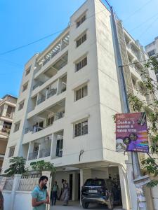 Akshra residency 1 bhk في هنجاودي: مبنى ابيض فيه ناس واقفه خارجه