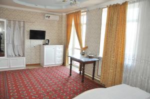 a bedroom with a bed and a desk and windows at Шинам Мехмонхонаси in Eshonguzar