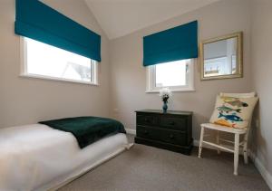 um quarto com cortinas azuis e uma cama e uma cadeira em Lluesta Cottage em Abersoch