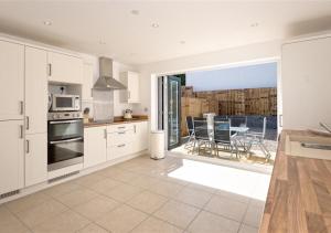 a kitchen with white cabinets and a view of the ocean at 8 Tai Dyffryn in Abersoch
