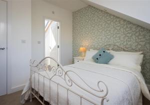 a bedroom with a white bed and a window at 8 Tai Dyffryn in Abersoch