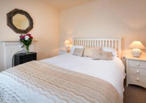 a bedroom with a white bed and a mirror at Bronwydd in Abersoch