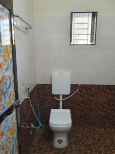 a bathroom with a white toilet and a window at SWAMI HOMESTAY in Mirya
