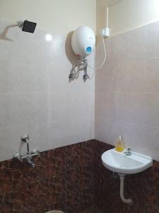 un bagno con lavandino bianco e un oggetto strano sul muro di SWAMI HOMESTAY a Mirya