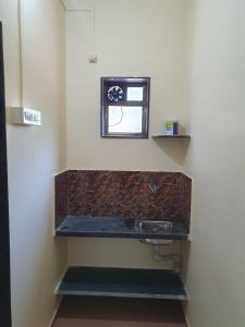 baño con lavabo, espejo y ventana en SWAMI HOMESTAY, en Mirya