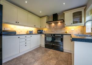 a kitchen with white cabinets and black appliances at Bragdy Wern in Llanbedrog