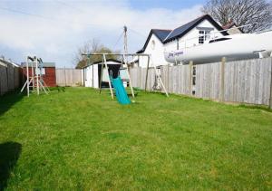 a yard with a playground with a plane over a fence at Wendon in Abersoch