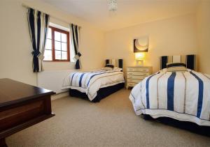 a bedroom with two beds and a dresser and a window at Y Betws in Abersoch