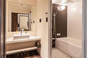 a bathroom with a sink and a bath tub at Apartment Hotel 11 Shinsaibashi AMEMURA in Osaka