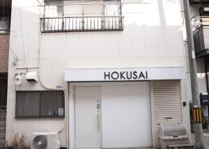 a white building with a hoxka sign above a door at Hokusai Stay in Osaka