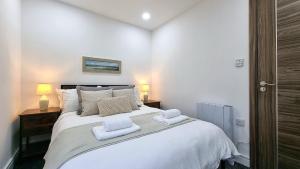 una camera da letto con un grande letto bianco con asciugamani di Top floor apartment in central Buxton a Buxton