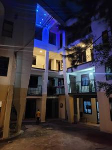 un edificio con un hombre de pie delante de él por la noche en EQUATOR GATES HOTEL, en Bulenga