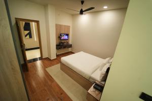 Dormitorio pequeño con cama y TV en THE CONTINENTAL INN & SUITES, en Mysore