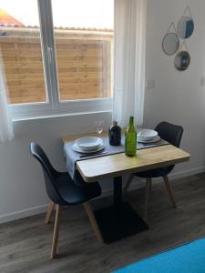 a wooden table with two chairs and a bottle on it at Studio neuf à Bouguenais+terrasse+parking in Bouguenais