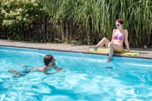 a man and a woman sitting in a swimming pool at Landhotel Schwabenhof in Heiligenbrunn +59 photos
