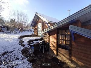 una cabaña de madera con nieve en el suelo al lado en Les abris de la hulotte, en Anould