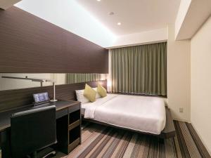 1 dormitorio con 1 cama y escritorio con ordenador en Hotel Brighton City Osaka Kitahama en Osaka
