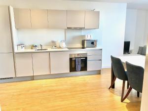 a kitchen with white cabinets and a table and chairs at Berks Luxury Serviced Apartments RWH 76 1 Bedroom, 1 super king bed, free parking, gym & wifi in Bracknell