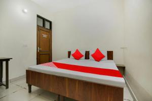 ein Schlafzimmer mit einem Bett mit roten Kissen darauf in der Unterkunft Wave Inn Guest House in Ludhiana