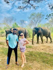 Un uomo e una donna in piedi di fronte agli elefanti di Sheran Safari House a Udawalawe