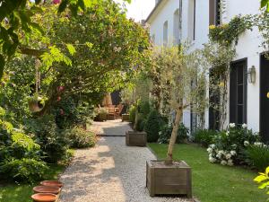 un jardin avec une passerelle avec un arbre et des plantes dans l'établissement Côté Baie, à Saint-Valery-sur-Somme