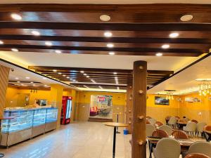 un restaurante con paredes amarillas, mesas y sillas en SN hotel inn and restaurant, en Sikandarābād